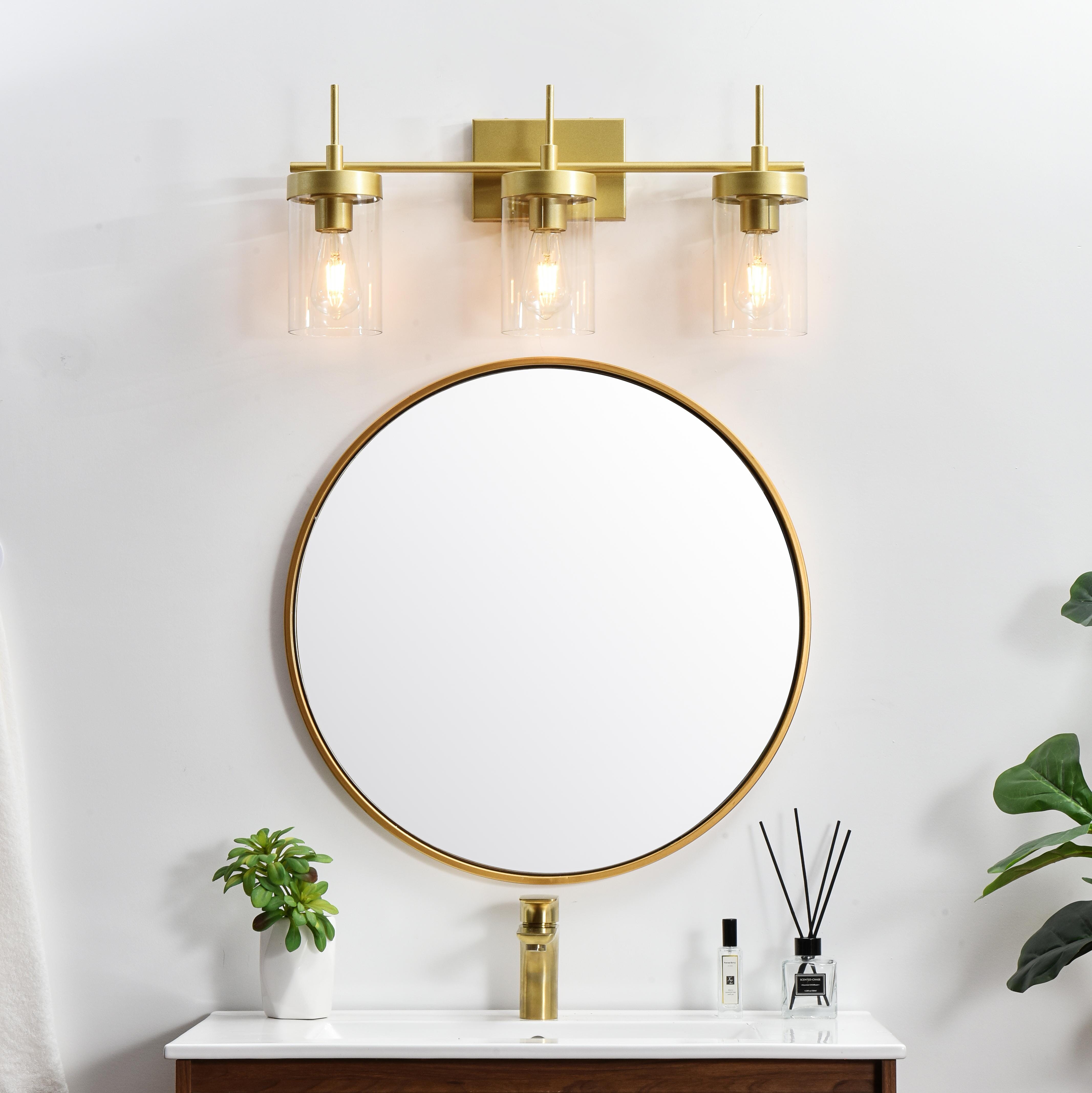 Defined by curved metal arm extends to suspend the clear bell glass shade. A contemporary stunner, it shows off the straight line details from the backplate and the streamline thin metal arm. Compatible with dimmers, so you'll have the right amount of light in any given time of the day. Completely versatile, you can place this wall light as an uplight or downlight. Rated for use in damp locations, this will work perfectly over a vanity in your bathroom. Collection: Benny Rooms: Bathroom Finish: Brass and Clear Glass: Clear Width: 24.00" Height: 11.00" Weight: 5.00 lb Extension from Wall: 6.00" Wire: 8" Black and White Canopy: 7.1"x4.7"x0.8" Number of Bulbs: 3 Maximum Wattage: 40.00 W Bulb Type: E26 Bulb Base: E26 Dimmable Voltage: 110.00 V Material: Iron and Glass Country of Origin: China Safety Listing: ETL Safety Rating: Damp Title 20 Title 24 Manufacturer Warranty: 1 year limited - alternate view