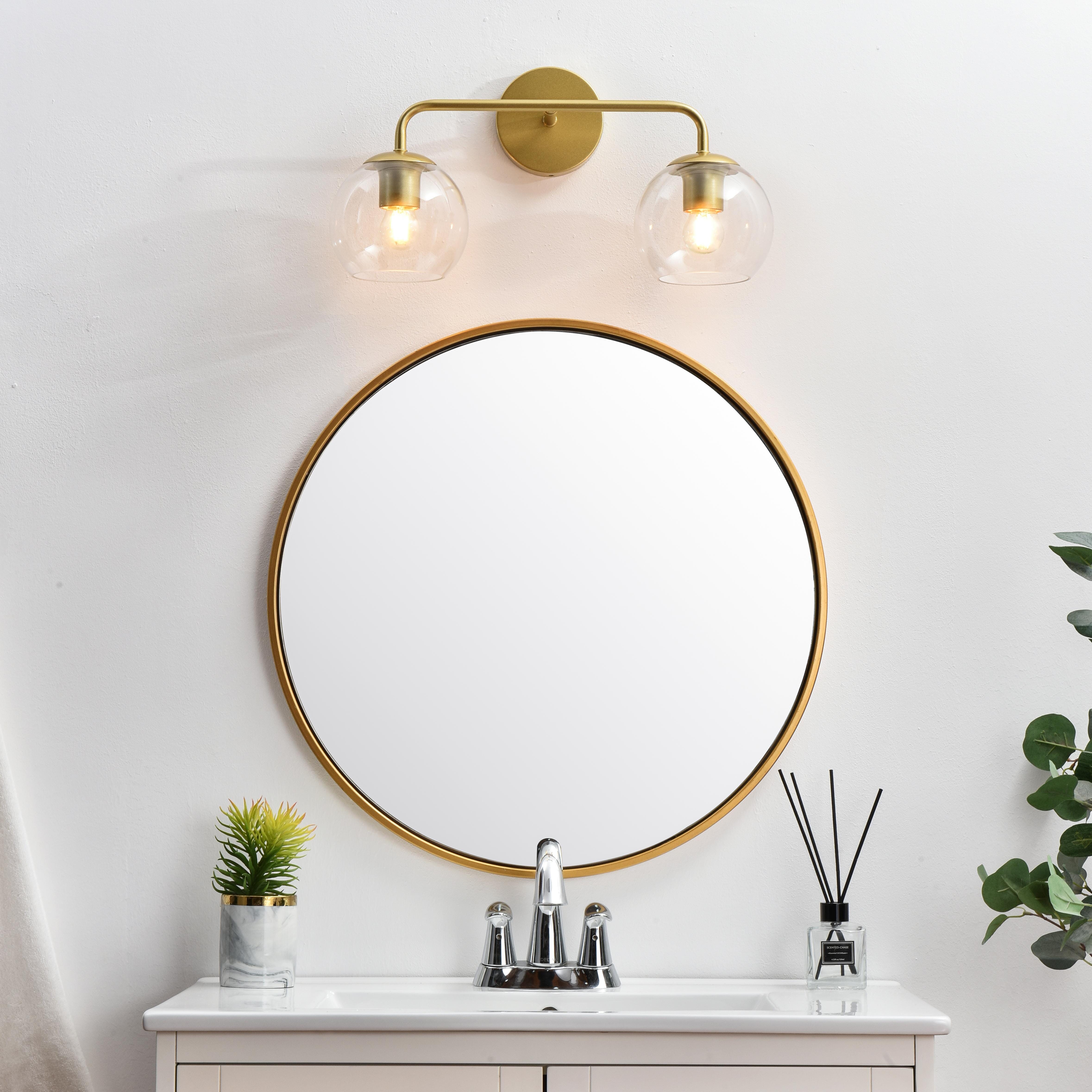 A modern twist on a traditional design, this vanity light is perfect for sprucing up your bathroom. Rated for use in damp locations, this iron fixture features a round backplate, curved arms, and orb accents. Completely versatile, you can place this wall light as an uplight or downlight. Rated for use in damp locations, this will work perfectly over a vanity in your bathroom. Collection: Genesis Rooms: Bathroom Finish: Brass and Clear Glass: Clear Width: 19.00" Height: 10.00" Weight: 2.00 lb Extension from Wall: 8.00" Wire: 8" Black and White Canopy: 4.7"x1"x4.7" Number of Bulbs: 2 Maximum Wattage: 40.00 W Bulb Type: E26 Bulb Base: E26 Dimmable Voltage: 110.00 V Material: Iron and Glass Country of Origin: China Safety Listing: ETL Safety Rating: Damp Title 20 Title 24 Manufacturer Warranty: 1 year limited - alternate view