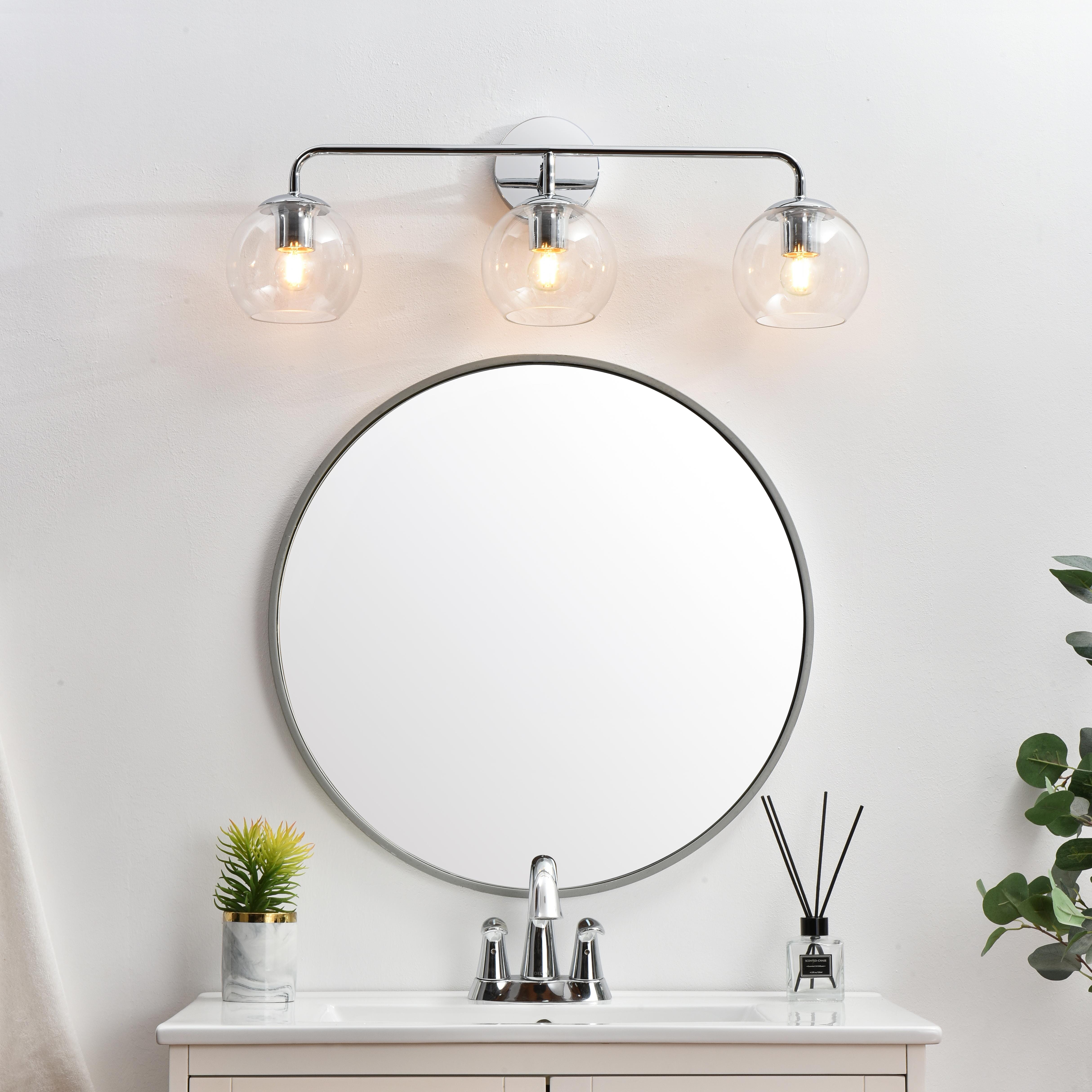 A modern twist on a traditional design, this vanity light is perfect for sprucing up your bathroom. Rated for use in damp locations, this iron fixture features a round backplate, curved arms, and orb accents. Completely versatile, you can place this wall light as an uplight or downlight. Rated for use in damp locations, this will work perfectly over a vanity in your bathroom. Collection: Genesis Rooms: Bathroom Finish: Chrome and Clear Glass: Clear Width: 28.00" Height: 10.00" Weight: 3.00 lb Extension from Wall: 8.00" Wire: 8" Black and White Canopy: 4.7"x1"x4.7" Number of Bulbs: 3 Maximum Wattage: 40.00 W Bulb Type: E26 Bulb Base: E26 Dimmable Voltage: 110.00 V Material: Iron and Glass Country of Origin: China Safety Listing: ETL Safety Rating: Damp Title 20 Title 24 Manufacturer Warranty: 1 year limited - alternate view