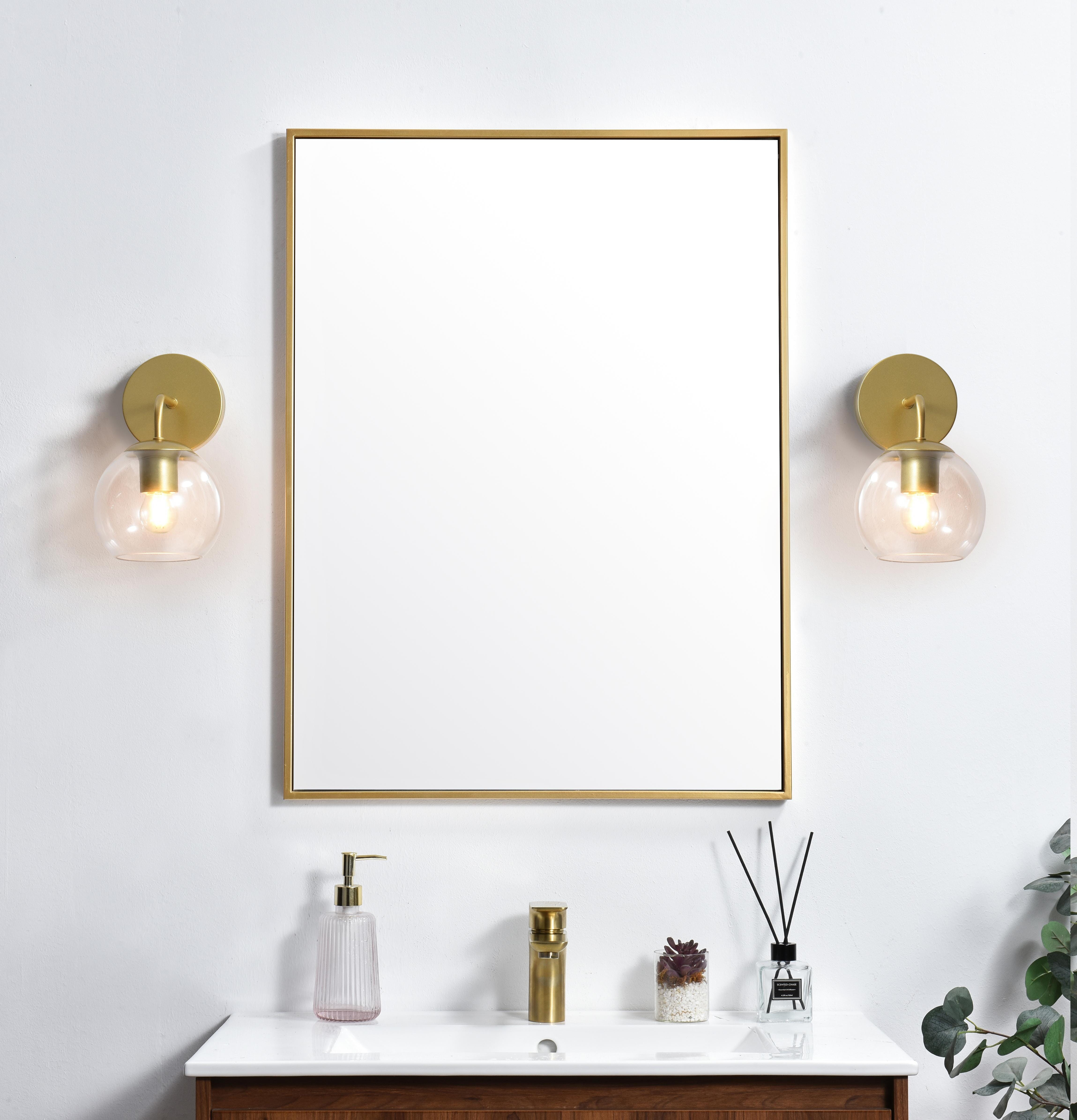 A modern twist on a traditional design, this vanity light is perfect for sprucing up your bathroom. Rated for use in damp locations, this iron fixture features a round backplate, curved arms, and orb accents. Completely versatile, you can place this wall light as an uplight or downlight. Rated for use in damp locations, this will work perfectly over a vanity in your bathroom. Collection: Genesis Rooms: Bathroom Finish: Brass and Clear Glass: Clear Width: 6.00" Height: 10.00" Weight: 1.00 lb Extension from Wall: 8.00" Wire: 8" Black and White Canopy: 4.7"x1"x4.7" Number of Bulbs: 1 Maximum Wattage: 40.00 W Bulb Type: E26 Bulb Base: E26 Dimmable Voltage: 110.00 V Material: Iron and Glass Country of Origin: China Safety Listing: ETL Safety Rating: Damp Title 20 Title 24 Manufacturer Warranty: 1 year limited - alternate view
