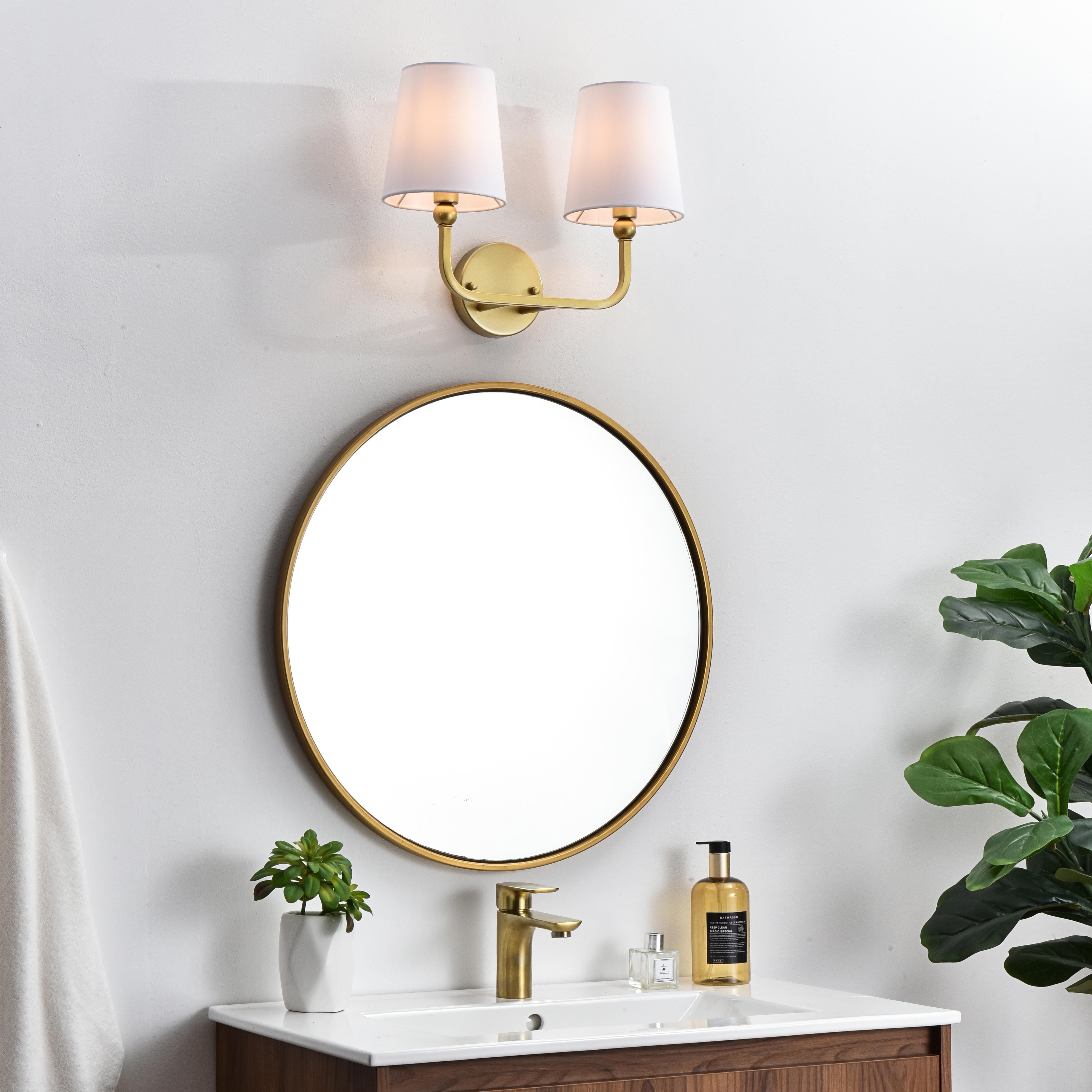 A modern twist on a traditional design, this vanity light is perfect for sprucing up your bathroom. Rated for use in damp locations, this iron fixture features a round backplate, curved arms, and fabric shade accents. Completely versatile, you can place this wall light as an uplight or downlight. Rated for use in damp locations, this will work perfectly over a vanity in your bathroom. Collection: Colson Rooms: Bathroom Finish: Brass and Clear Glass: White Width: 16.00" Height: 12.00" Weight: 2.00 lb Extension from Wall: 7.50" Wire: 8" Black and White Canopy: 4.7"x1"x4.7" Number of Bulbs: 2 Maximum Wattage: 40.00 W Bulb Type: E12 Bulb Base: E12 Dimmable Voltage: 110.00 V Material: Metal and Fabric shade Country of Origin: China Safety Listing: ETL Safety Rating: Damp Title 20 Title 24 Manufacturer Warranty: 1 year limited - alternate view
