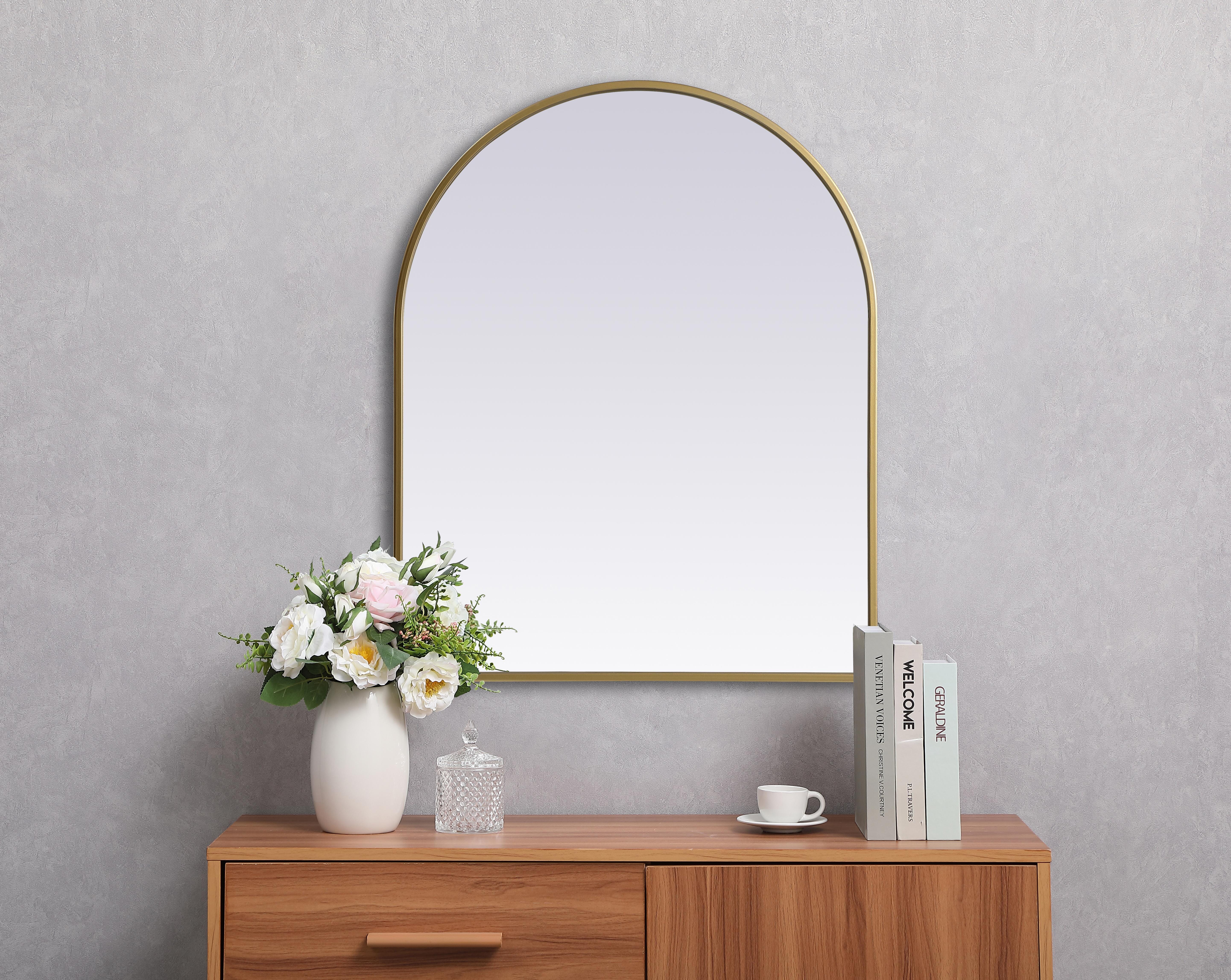 Instantly open up any space in your home with this minimalist wall-mounted mirror. Crafted of metal, this mirror strikes a round silhouette. Its slender, clean-lined frame sports a classic finish, while the glass mirror within features a flat, for a brilliant reflection, letting the light bounce off to expand your space. Designed in an arch shape, this metal-frame mirror showcases in the three available satin finishes in black, brass, or silver. Mount this work of art in any room of your choice for added visual impact. Collection: Ayra Finish: Brass Width: 24.00" Height: 30.00" Length: 30.00" Weight: 13.00 lb Material: iron and MDF Country of Origin: China Manufacturer Warranty: 1 year limited - alternate view
