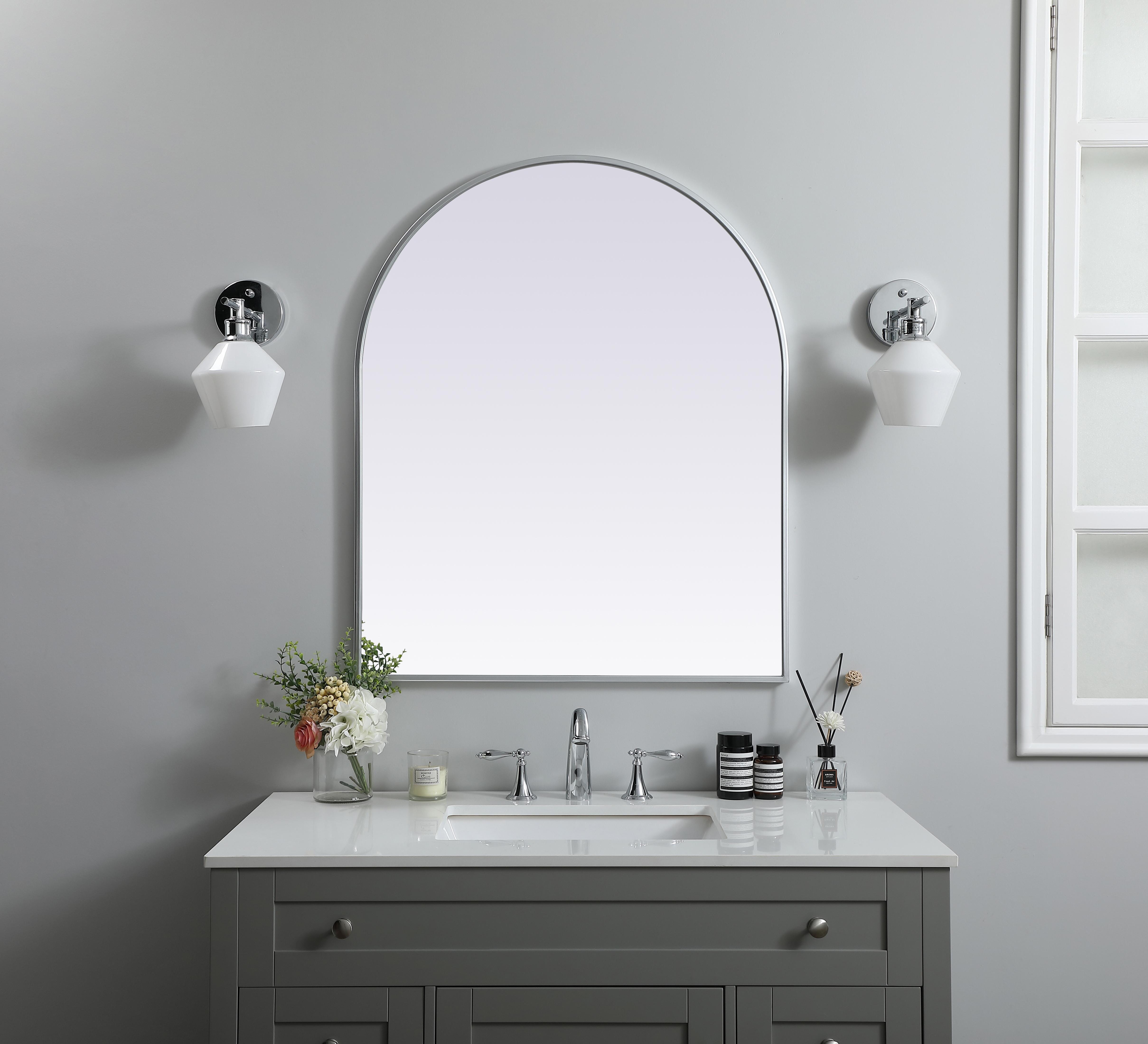 Instantly open up any space in your home with this minimalist wall-mounted mirror. Crafted of metal, this mirror strikes a round silhouette. Its slender, clean-lined frame sports a classic finish, while the glass mirror within features a flat, for a brilliant reflection, letting the light bounce off to expand your space. Designed in an arch shape, this metal-frame mirror showcases in the three available satin finishes in black, brass, or silver. Mount this work of art in any room of your choice for added visual impact. Collection: Ayra Finish: Silver Width: 30.00" Height: 36.00" Length: 36.00" Weight: 19.00 lb Material: iron and MDF Country of Origin: China Manufacturer Warranty: 1 year limited - alternate view