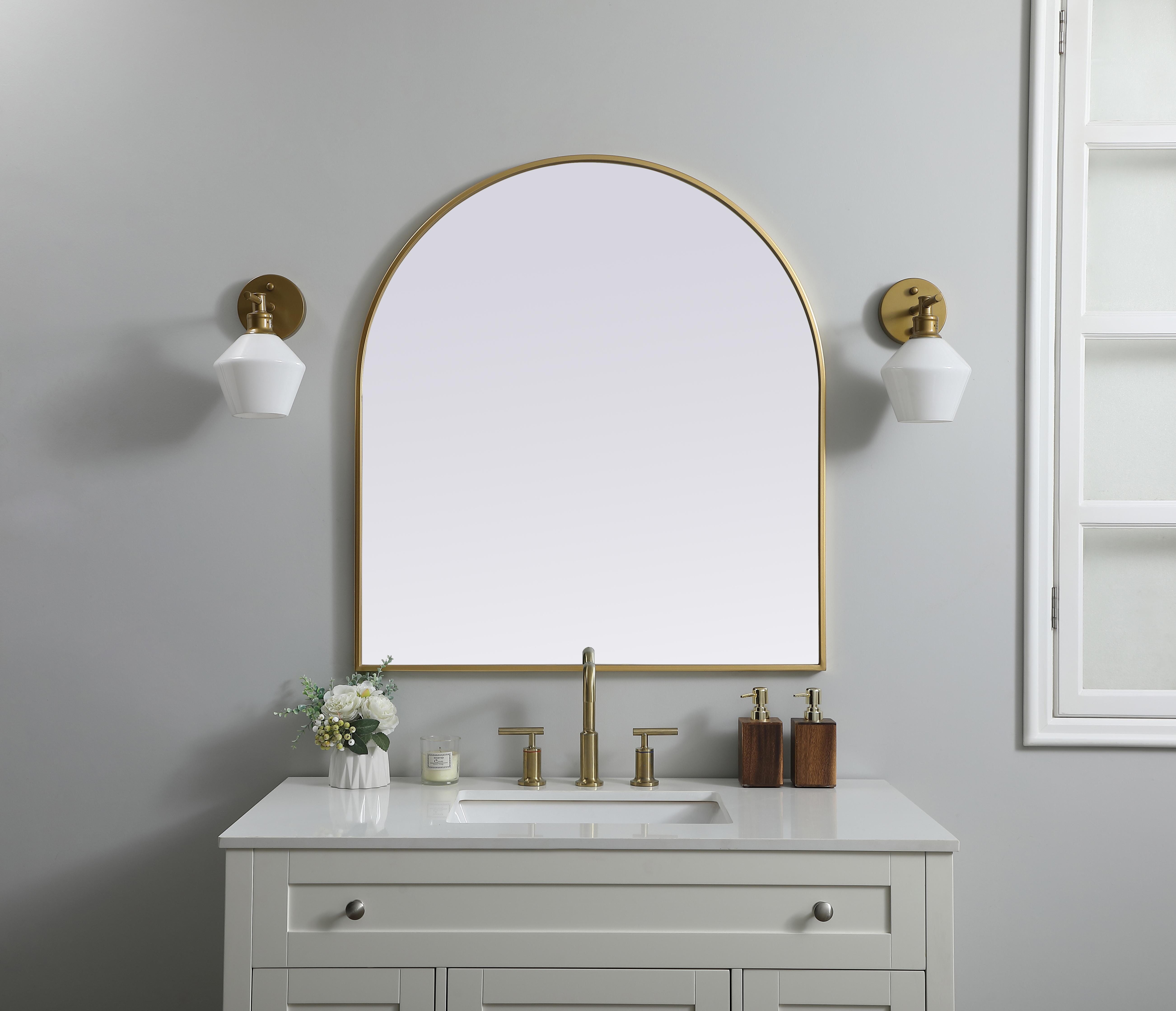 Instantly open up any space in your home with this minimalist wall-mounted mirror. Crafted of metal, this mirror strikes a round silhouette. Its slender, clean-lined frame sports a classic finish, while the glass mirror within features a flat, for a brilliant reflection, letting the light bounce off to expand your space. Designed in an arch shape, this metal-frame mirror showcases in the three available satin finishes in black, brass, or silver. Mount this work of art in any room of your choice for added visual impact. Collection: Ayra Finish: Brass Width: 33.00" Height: 36.00" Length: 36.00" Weight: 21.00 lb Material: iron and MDF Country of Origin: China Manufacturer Warranty: 1 year limited - alternate view