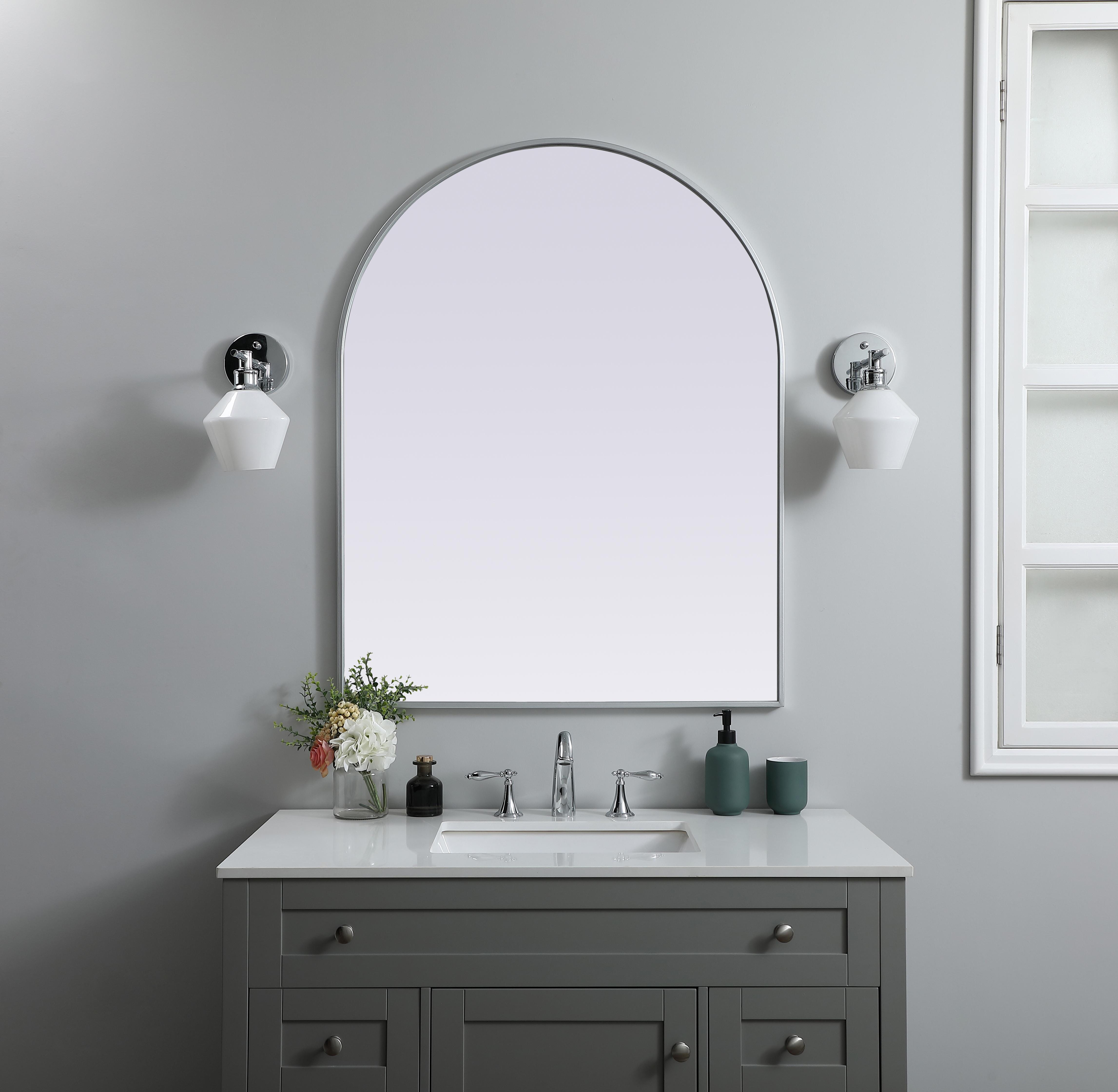 Instantly open up any space in your home with this minimalist wall-mounted mirror. Crafted of metal, this mirror strikes a round silhouette. Its slender, clean-lined frame sports a classic finish, while the glass mirror within features a flat, for a brilliant reflection, letting the light bounce off to expand your space. Designed in an arch shape, this metal-frame mirror showcases in the three available satin finishes in black, brass, or silver. Mount this work of art in any room of your choice for added visual impact. Collection: Ayra Finish: Silver Width: 33.00" Height: 42.00" Length: 42.00" Weight: 24.00 lb Material: iron and MDF Country of Origin: China Manufacturer Warranty: 1 year limited - alternate view