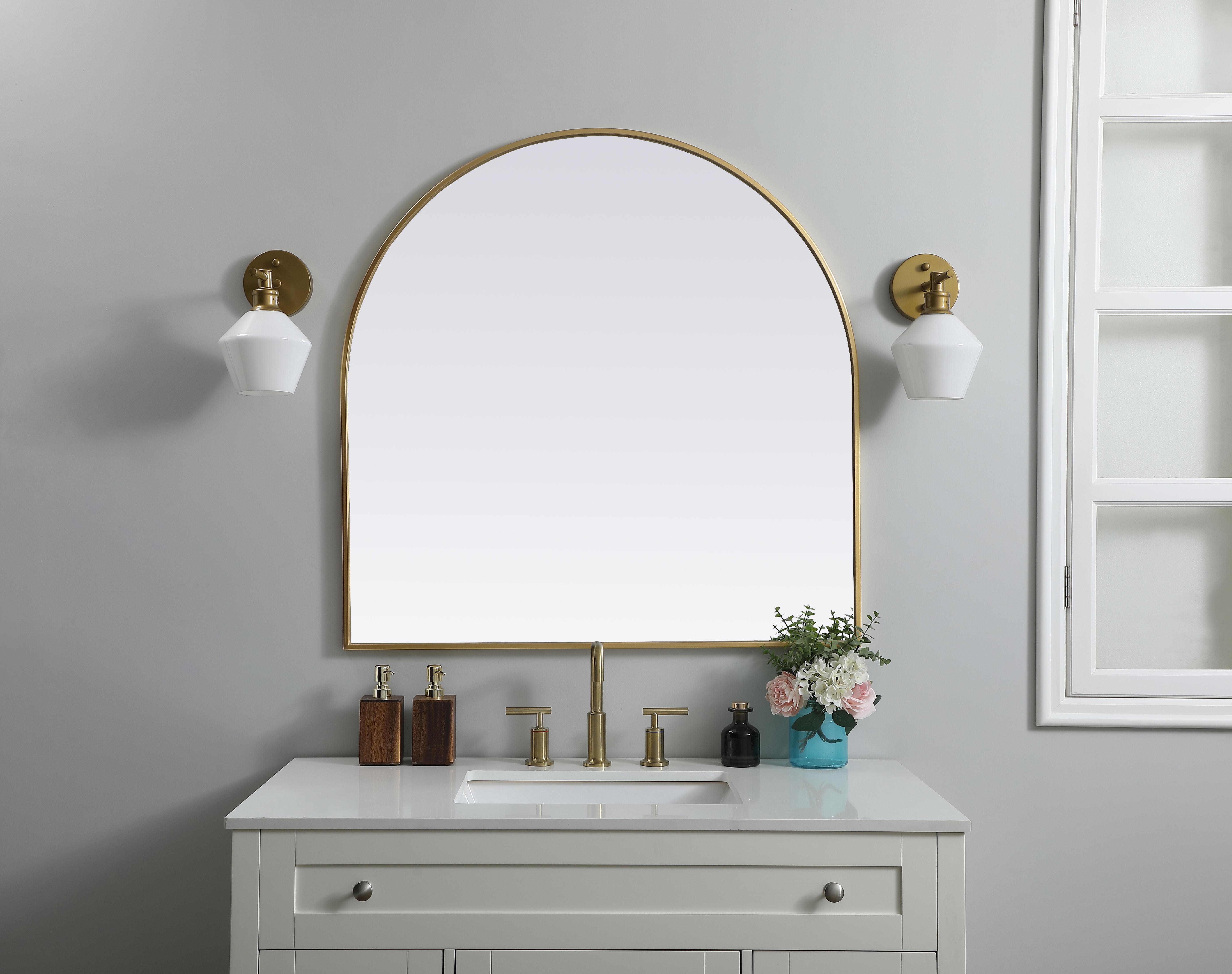 Instantly open up any space in your home with this minimalist wall-mounted mirror. Crafted of metal, this mirror strikes a round silhouette. Its slender, clean-lined frame sports a classic finish, while the glass mirror within features a flat, for a brilliant reflection, letting the light bounce off to expand your space. Designed in an arch shape, this metal-frame mirror showcases in the three available satin finishes in black, brass, or silver. Mount this work of art in any room of your choice for added visual impact. Collection: Ayra Finish: Brass Width: 36.00" Height: 36.00" Length: 36.00" Weight: 22.00 lb Material: iron and MDF Country of Origin: China Manufacturer Warranty: 1 year limited - alternate view