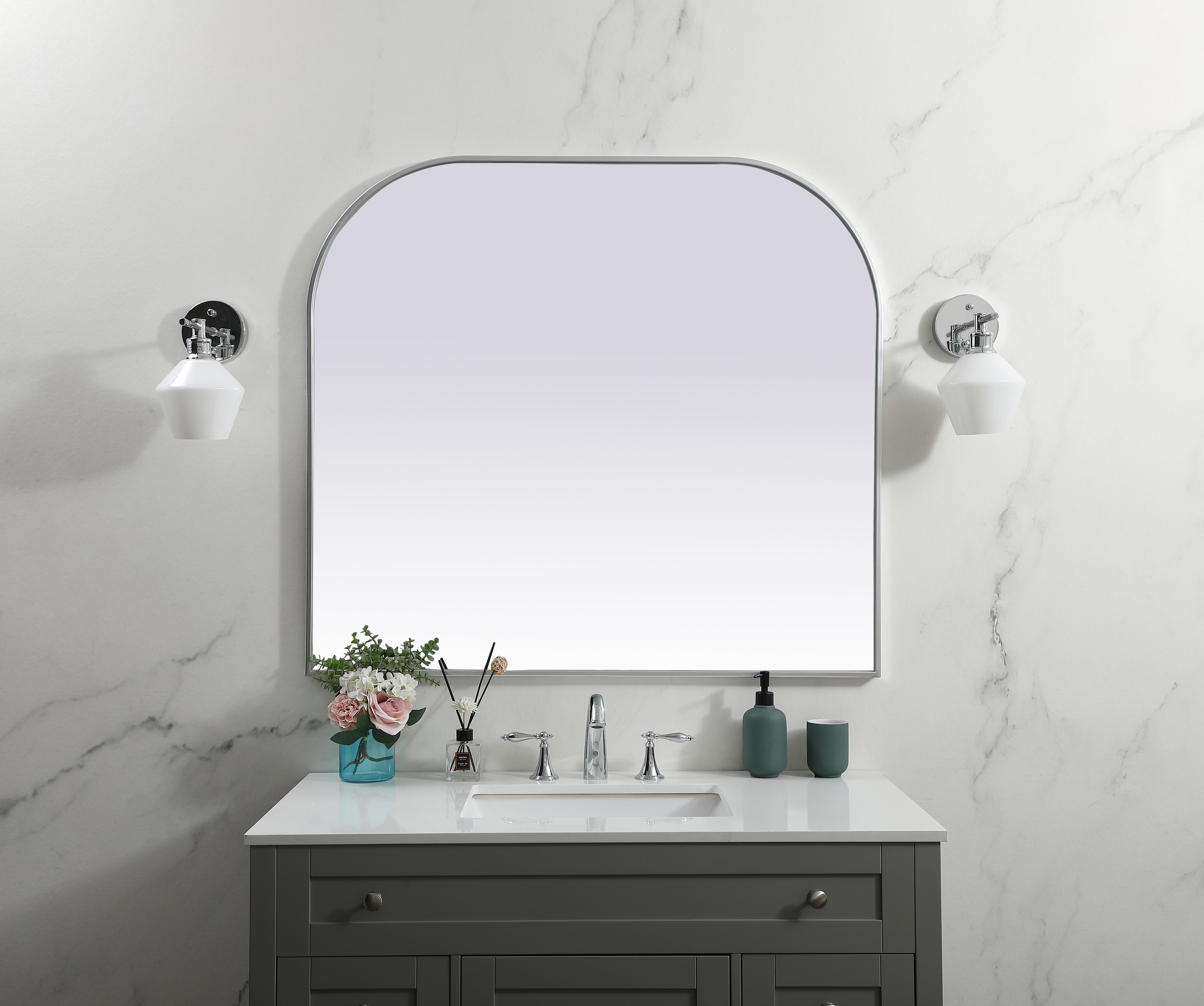 Over the mantel mirror serves an ideal décor on the mantel because it acts as an anchor piece that you can accentuate around with smaller accessories. The reflective qualities of the mirror can also make a space look bigger and brighter since it bounces light coming from your light sources. Designed with square bottom edges and rounded top, this mirror gives an unexpected twist to your typical mirror look. Select from three satin finishes in black, brass, or silver. Collection: Blaire Finish: Silver Width: 42.00" Height: 38.00" Length: 38.00" Weight: 28.00 lb Material: iron and MDF Country of Origin: China Manufacturer Warranty: 1 year limited - alternate view