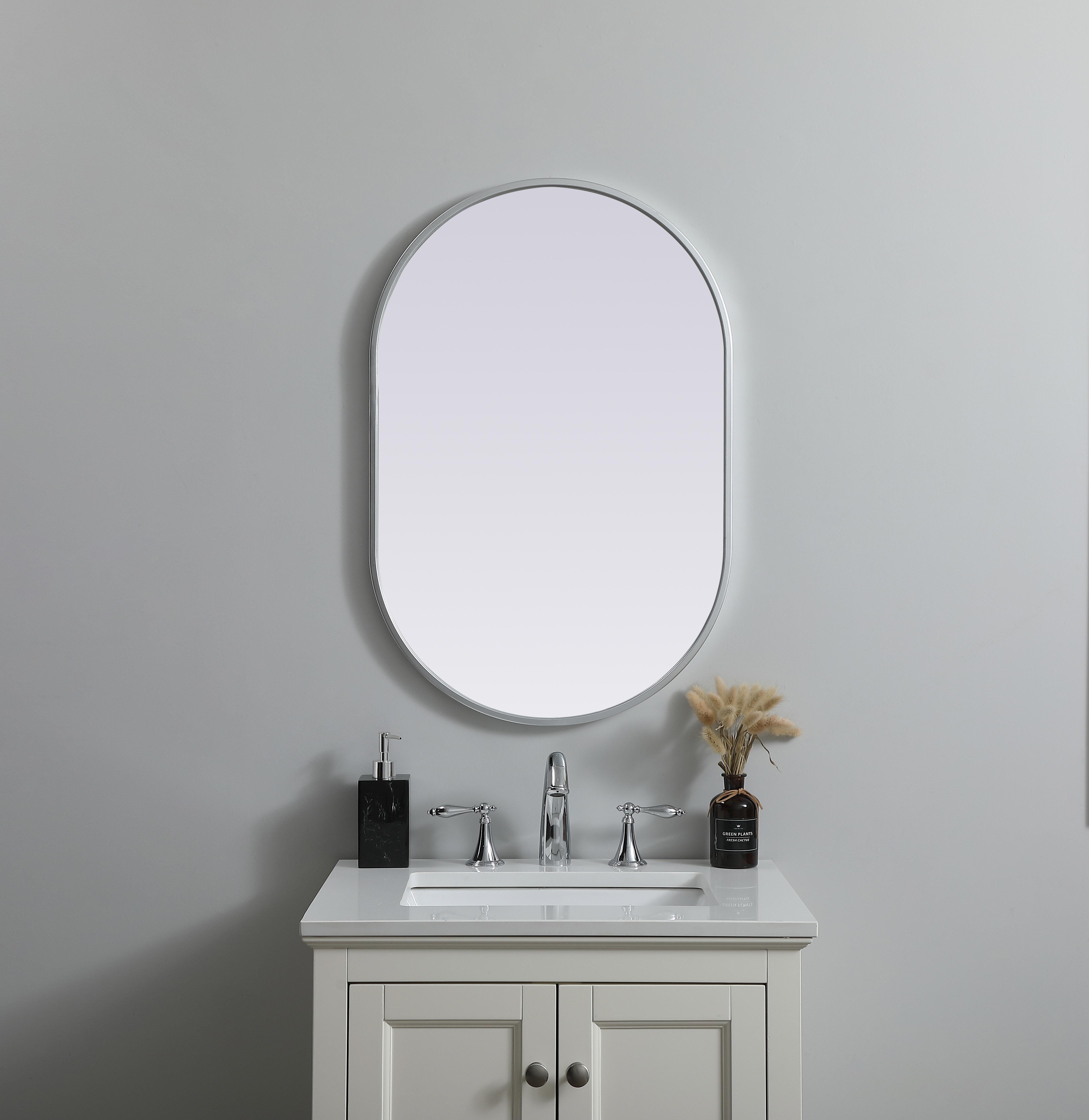 Instantly open up any space in your home with this minimalist wall-mounted mirror. Crafted of metal, this mirror strikes a pill-shaped silhouette. Its slender, clean-lined frame sports a classic finish, while the glass mirror within features a flat, for a brilliant reflection, letting the light bounce off to expand your space. Designed in a pill shape, this metal-frame mirror showcases in the three available satin finishes in black, brass, or silver. Mount this work of art in any room of your choice for added visual impact. Collection: Asha Finish: Silver Width: 20.00" Height: 30.00" Length: 30.00" Weight: 11.00 lb Material: iron and MDF Country of Origin: China Manufacturer Warranty: 1 year limited - alternate view