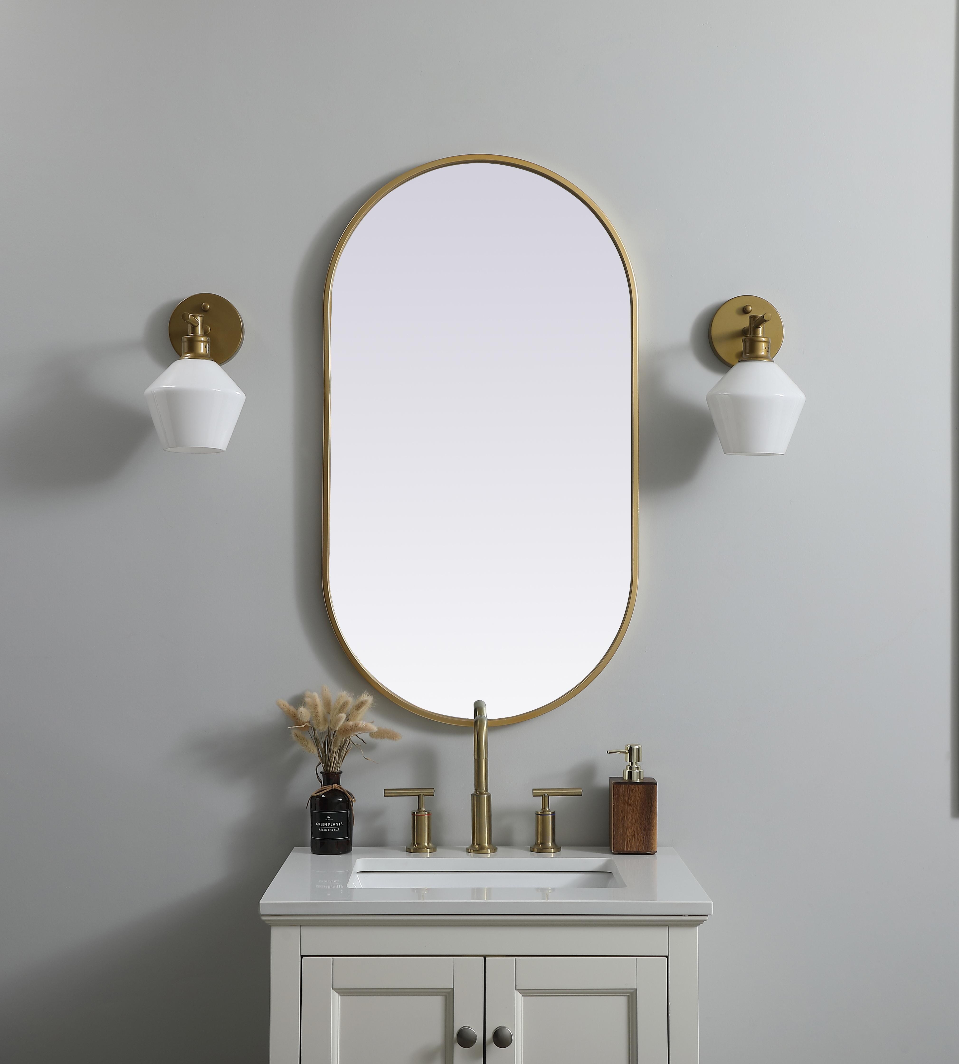Instantly open up any space in your home with this minimalist wall-mounted mirror. Crafted of metal, this mirror strikes a pill-shaped silhouette. Its slender, clean-lined frame sports a classic finish, while the glass mirror within features a flat, for a brilliant reflection, letting the light bounce off to expand your space. Designed in a pill shape, this metal-frame mirror showcases in the three available satin finishes in black, brass, or silver. Mount this work of art in any room of your choice for added visual impact. Collection: Asha Finish: Brass Width: 20.00" Height: 36.00" Length: 36.00" Weight: 13.00 lb Material: iron and MDF Country of Origin: China Manufacturer Warranty: 1 year limited - alternate view