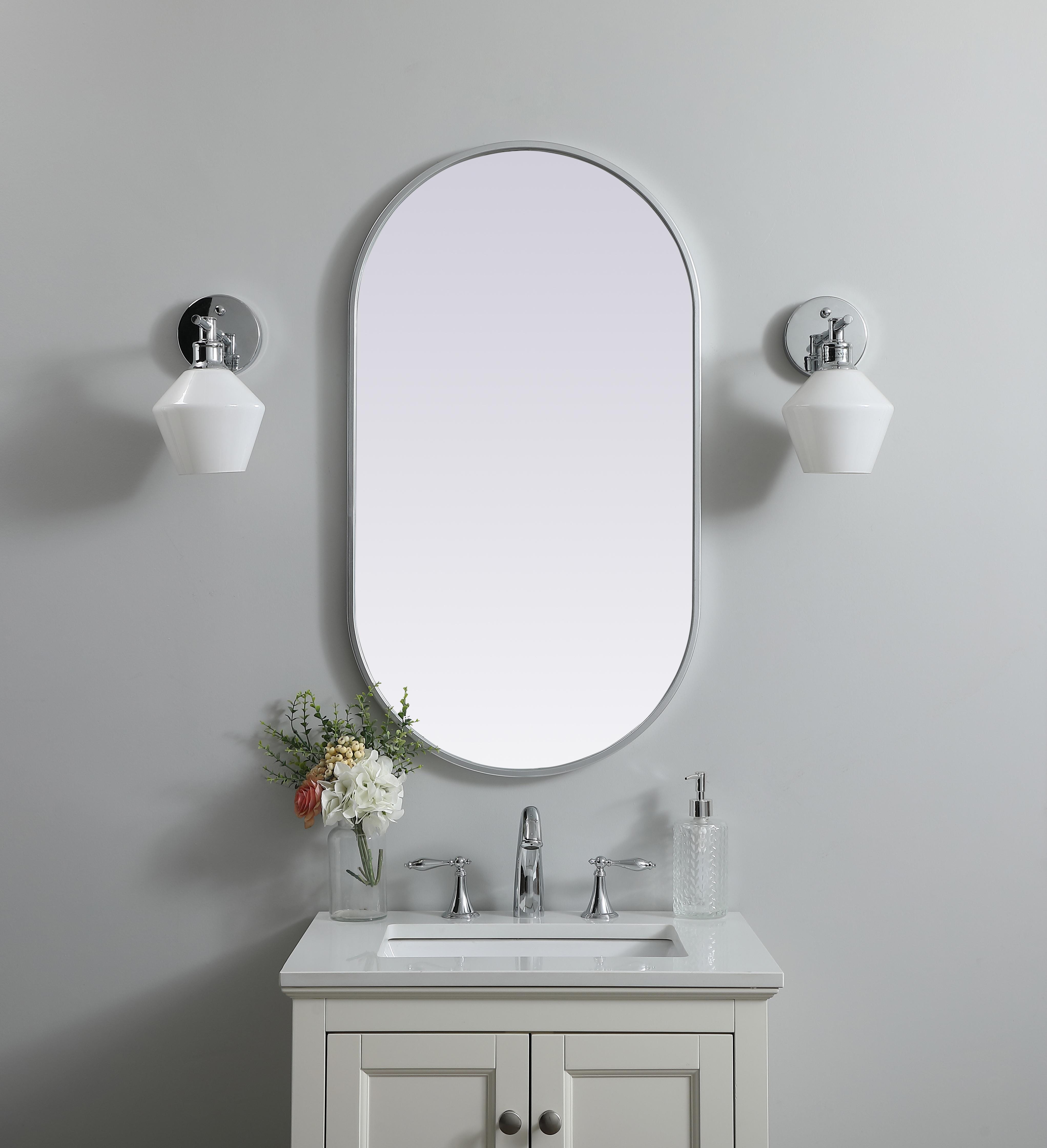 Instantly open up any space in your home with this minimalist wall-mounted mirror. Crafted of metal, this mirror strikes a pill-shaped silhouette. Its slender, clean-lined frame sports a classic finish, while the glass mirror within features a flat, for a brilliant reflection, letting the light bounce off to expand your space. Designed in a pill shape, this metal-frame mirror showcases in the three available satin finishes in black, brass, or silver. Mount this work of art in any room of your choice for added visual impact. Collection: Asha Finish: Silver Width: 20.00" Height: 36.00" Length: 36.00" Weight: 13.00 lb Material: iron and MDF Country of Origin: China Manufacturer Warranty: 1 year limited - alternate view