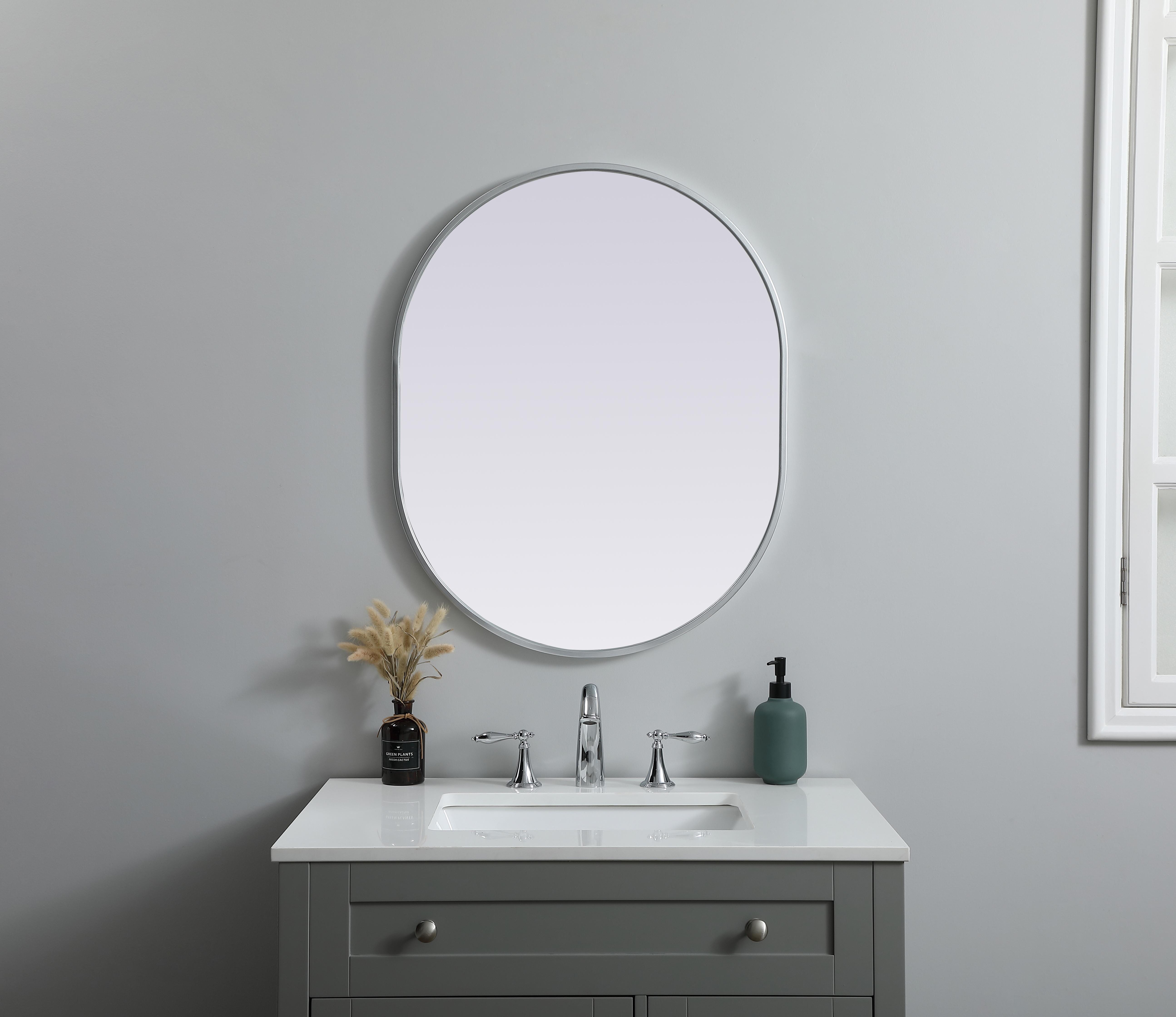 Instantly open up any space in your home with this minimalist wall-mounted mirror. Crafted of metal, this mirror strikes a pill-shaped silhouette. Its slender, clean-lined frame sports a classic finish, while the glass mirror within features a flat, for a brilliant reflection, letting the light bounce off to expand your space. Designed in a pill shape, this metal-frame mirror showcases in the three available satin finishes in black, brass, or silver. Mount this work of art in any room of your choice for added visual impact. Collection: Asha Finish: Silver Width: 24.00" Height: 30.00" Length: 30.00" Weight: 12.00 lb Material: iron and MDF Country of Origin: China Manufacturer Warranty: 1 year limited - alternate view