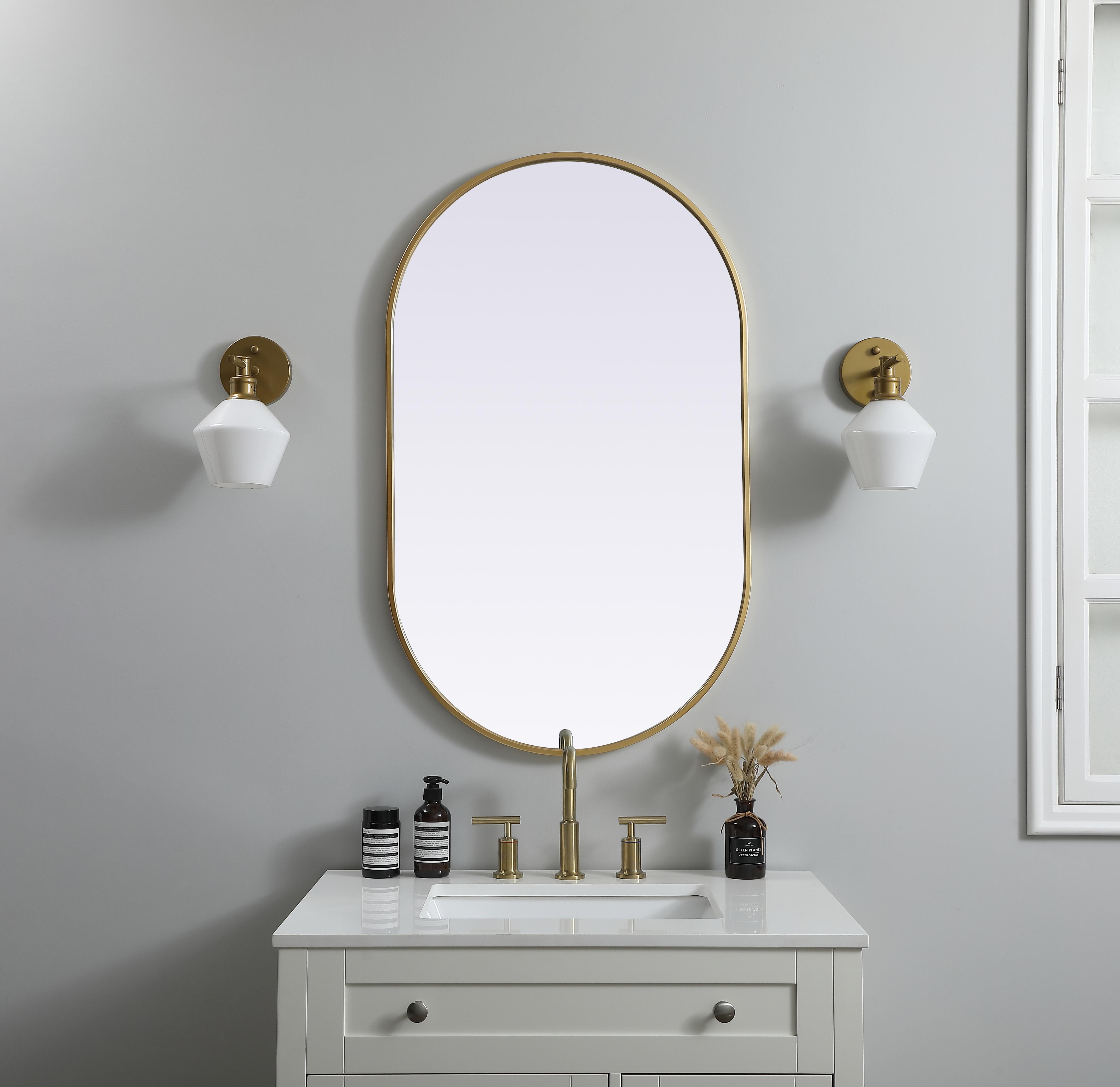 Instantly open up any space in your home with this minimalist wall-mounted mirror. Crafted of metal, this mirror strikes a pill-shaped silhouette. Its slender, clean-lined frame sports a classic finish, while the glass mirror within features a flat, for a brilliant reflection, letting the light bounce off to expand your space. Designed in a pill shape, this metal-frame mirror showcases in the three available satin finishes in black, brass, or silver. Mount this work of art in any room of your choice for added visual impact. Collection: Asha Finish: Brass Width: 24.00" Height: 40.00" Length: 40.00" Weight: 16.00 lb Material: iron and MDF Country of Origin: China Manufacturer Warranty: 1 year limited - alternate view