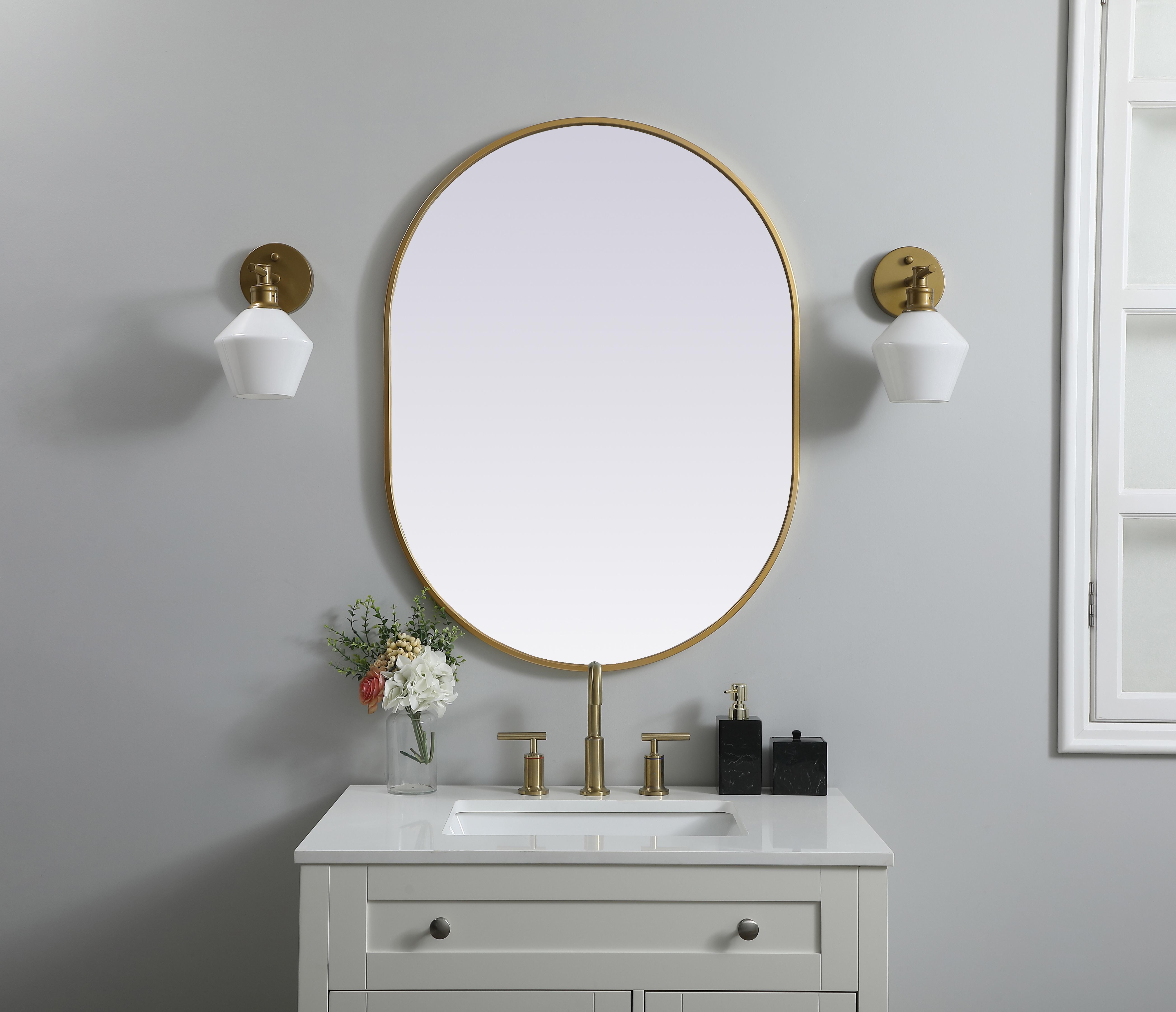 Instantly open up any space in your home with this minimalist wall-mounted mirror. Crafted of metal, this mirror strikes a pill-shaped silhouette. Its slender, clean-lined frame sports a classic finish, while the glass mirror within features a flat, for a brilliant reflection, letting the light bounce off to expand your space. Designed in a pill shape, this metal-frame mirror showcases in the three available satin finishes in black, brass, or silver. Mount this work of art in any room of your choice for added visual impact. Collection: Asha Finish: Brass Width: 27.00" Height: 36.00" Length: 36.00" Weight: 16.00 lb Material: iron and MDF Country of Origin: China Manufacturer Warranty: 1 year limited - alternate view