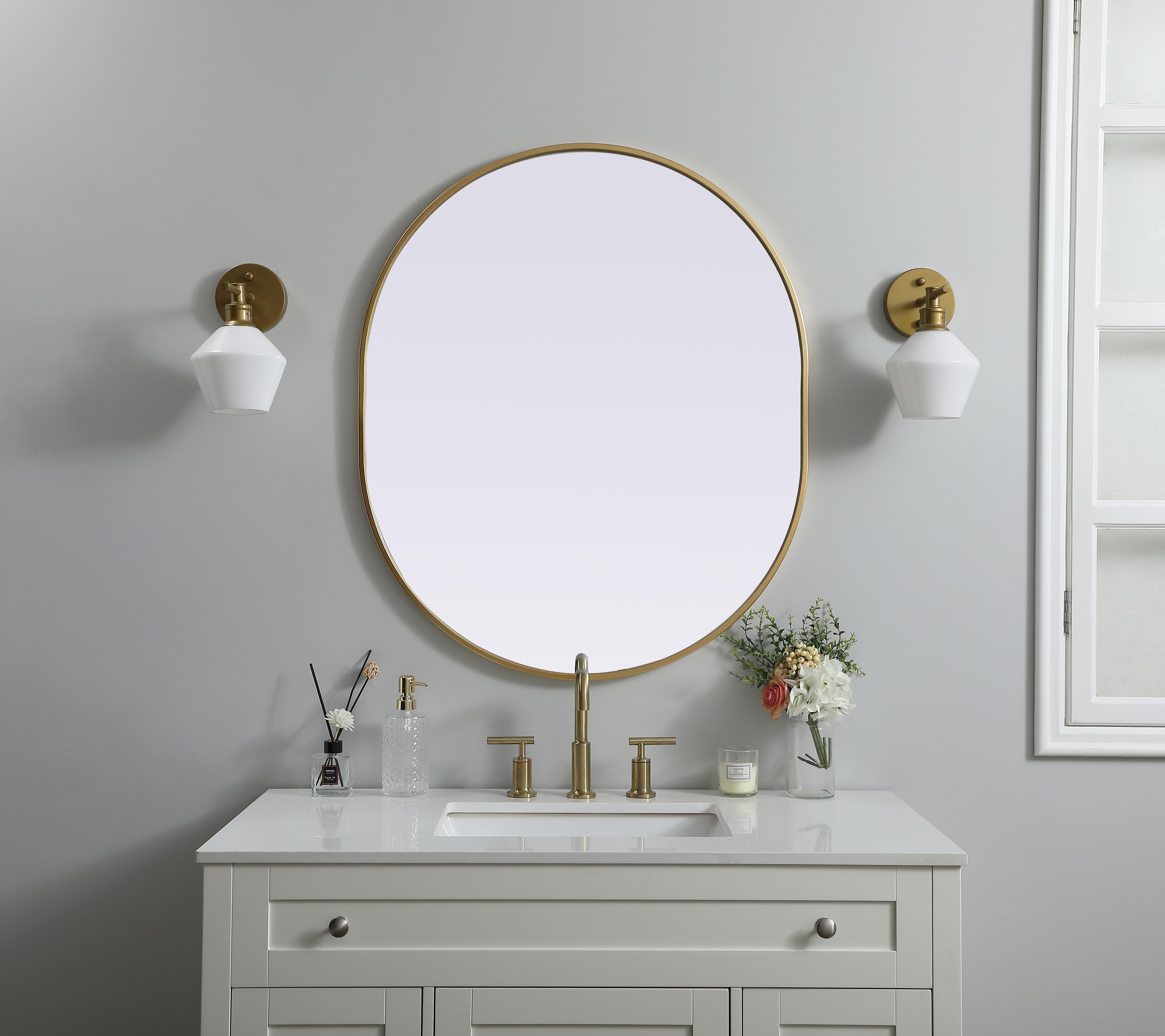 Instantly open up any space in your home with this minimalist wall-mounted mirror. Crafted of metal, this mirror strikes a pill-shaped silhouette. Its slender, clean-lined frame sports a classic finish, while the glass mirror within features a flat, for a brilliant reflection, letting the light bounce off to expand your space. Designed in a pill shape, this metal-frame mirror showcases in the three available satin finishes in black, brass, or silver. Mount this work of art in any room of your choice for added visual impact. Collection: Asha Finish: Brass Width: 30.00" Height: 36.00" Length: 36.00" Weight: 17.00 lb Material: iron and MDF Country of Origin: China Manufacturer Warranty: 1 year limited - alternate view