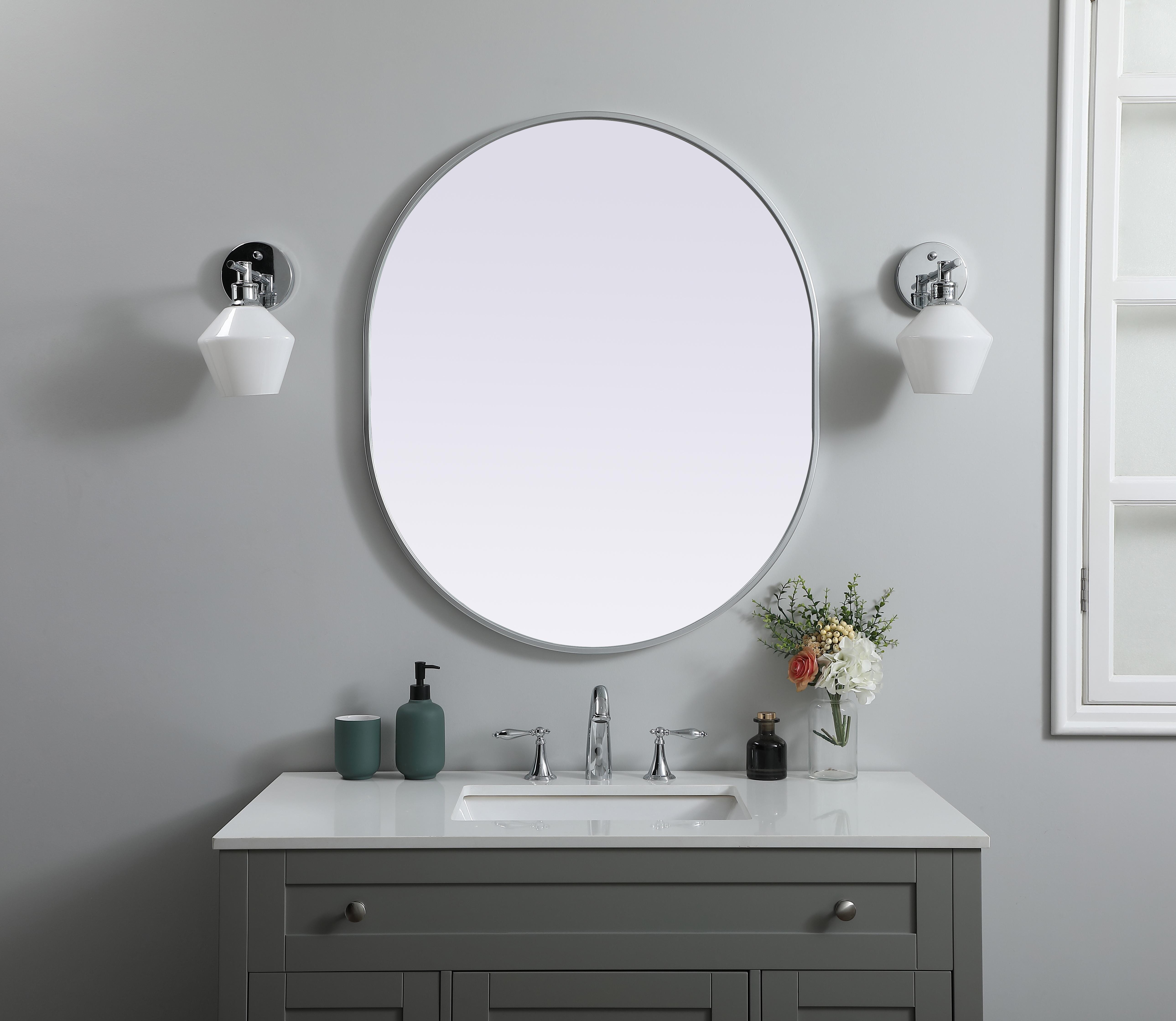 Instantly open up any space in your home with this minimalist wall-mounted mirror. Crafted of metal, this mirror strikes a pill-shaped silhouette. Its slender, clean-lined frame sports a classic finish, while the glass mirror within features a flat, for a brilliant reflection, letting the light bounce off to expand your space. Designed in a pill shape, this metal-frame mirror showcases in the three available satin finishes in black, brass, or silver. Mount this work of art in any room of your choice for added visual impact. Collection: Asha Finish: Silver Width: 30.00" Height: 36.00" Length: 36.00" Weight: 17.00 lb Material: iron and MDF Country of Origin: China Manufacturer Warranty: 1 year limited - alternate view
