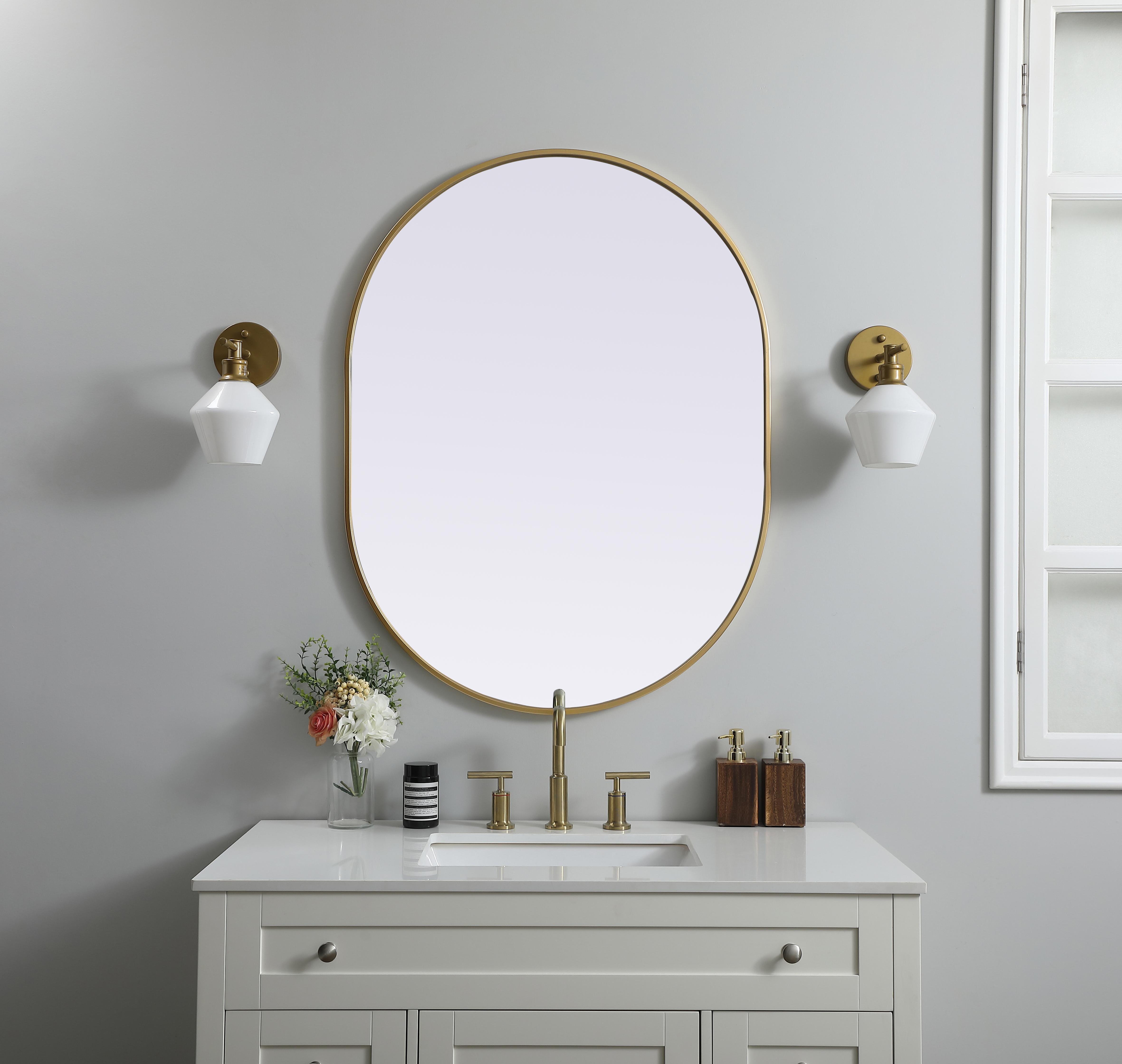 Instantly open up any space in your home with this minimalist wall-mounted mirror. Crafted of metal, this mirror strikes a pill-shaped silhouette. Its slender, clean-lined frame sports a classic finish, while the glass mirror within features a flat, for a brilliant reflection, letting the light bounce off to expand your space. Designed in a pill shape, this metal-frame mirror showcases in the three available satin finishes in black, brass, or silver. Mount this work of art in any room of your choice for added visual impact. Collection: Asha Finish: Brass Width: 30.00" Height: 40.00" Length: 40.00" Weight: 19.00 lb Material: iron and MDF Country of Origin: China Manufacturer Warranty: 1 year limited - alternate view