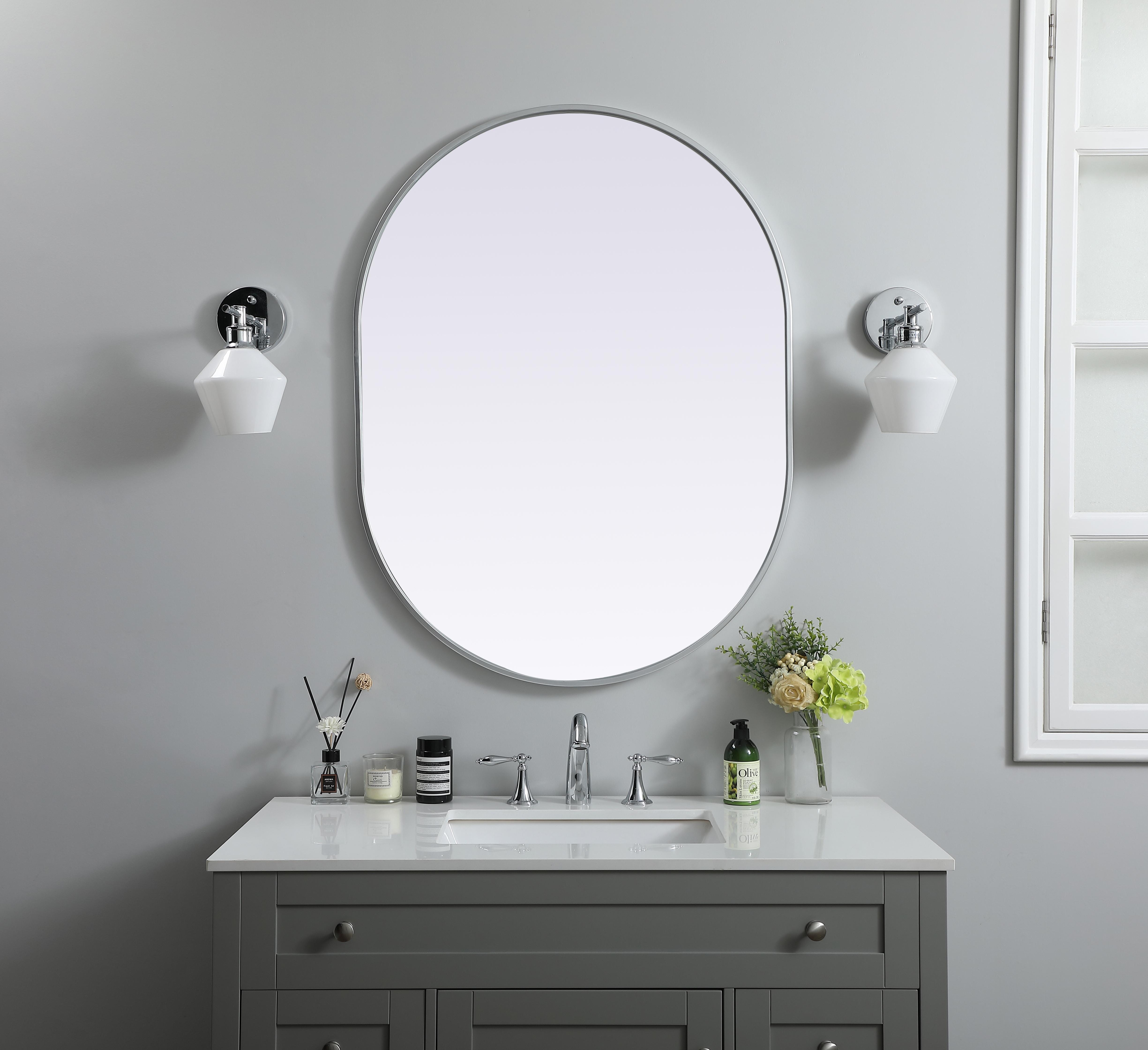 Instantly open up any space in your home with this minimalist wall-mounted mirror. Crafted of metal, this mirror strikes a pill-shaped silhouette. Its slender, clean-lined frame sports a classic finish, while the glass mirror within features a flat, for a brilliant reflection, letting the light bounce off to expand your space. Designed in a pill shape, this metal-frame mirror showcases in the three available satin finishes in black, brass, or silver. Mount this work of art in any room of your choice for added visual impact. Collection: Asha Finish: Silver Width: 30.00" Height: 40.00" Length: 40.00" Weight: 19.00 lb Material: iron and MDF Country of Origin: China Manufacturer Warranty: 1 year limited - alternate view