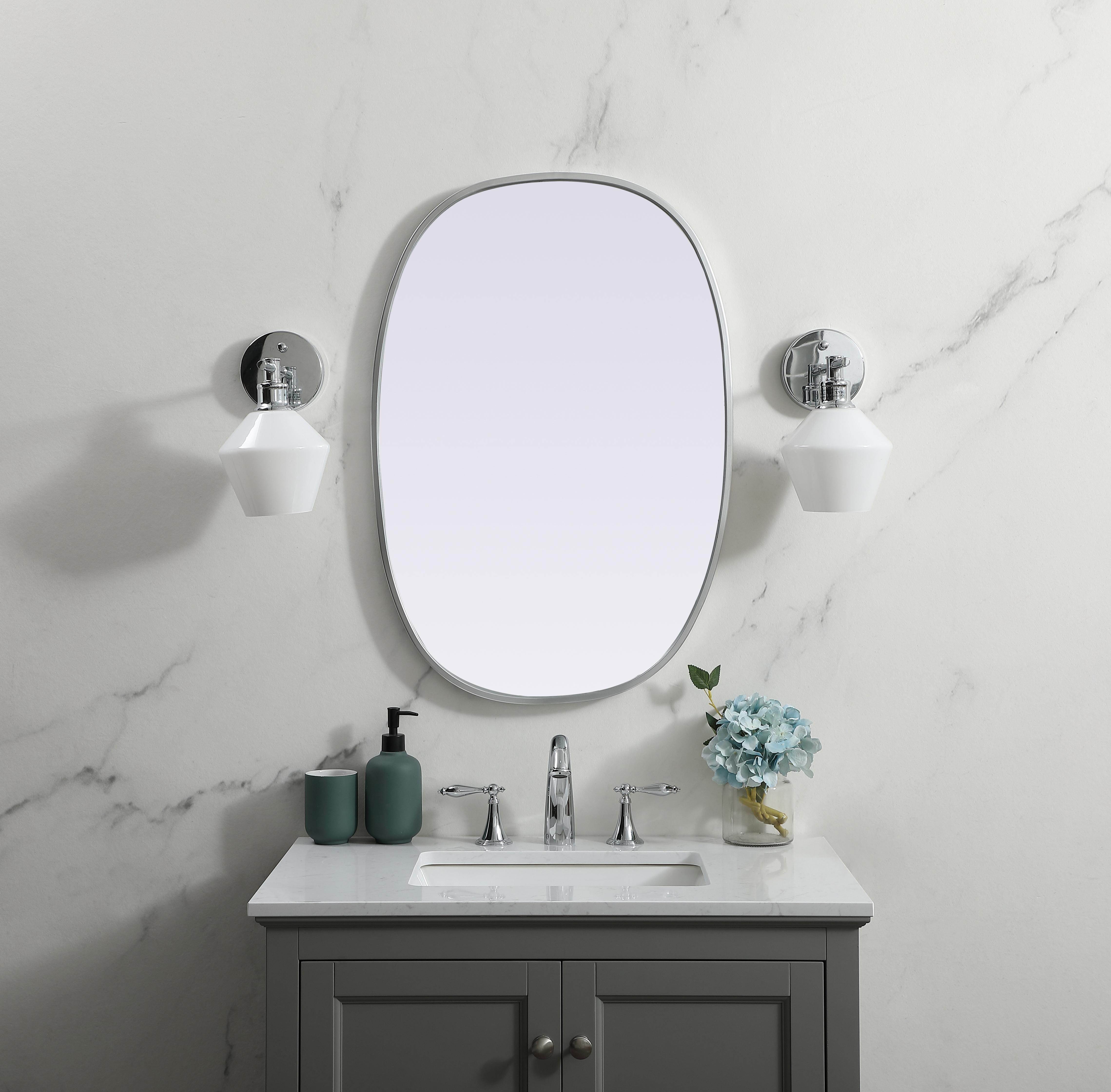 Crafted of metal, this mirror strikes a rounded corner silhouette. Instantly open up any space in your home with this minimalist wall-mounted mirror. Its slender, clean-lined frame sports a classic finish, while the glass mirror within features a flat, for a brilliant reflection, letting the light bounce off to expand your space. Designed in an oblong shape, this metal-frame mirror showcases in the three available satin finishes in black, brass, or silver. Mount this work of art in any room of your choice for added visual impact. Collection: Brynn Finish: Silver Width: 20.00" Height: 30.00" Length: 30.00" Weight: 11.00 lb Material: iron and MDF Country of Origin: China Manufacturer Warranty: 1 year limited - alternate view