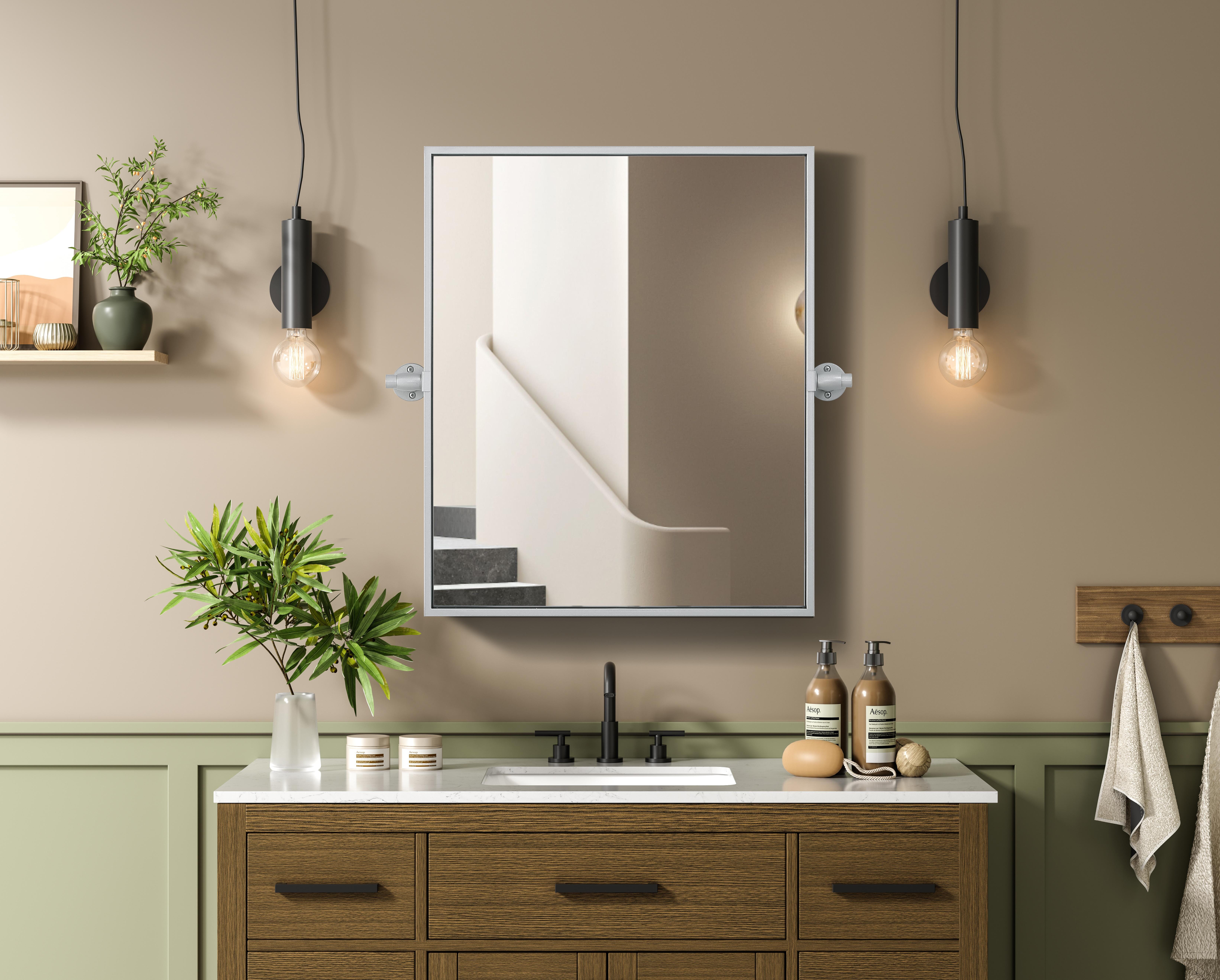 Upgrade your space with a modern pivot mirror that offers both form and function. Featuring an adjustable 8-degree tilt, this mirror allows you to customize your viewing angle for convenience and style. The iron frame with MDF backing ensures durability, while the hand-painted finish—available in black, silver, and brass—adds a touch of sophistication. Designed for versatility, this rectangular mirror can be mounted vertically or horizontally, making it the perfect fit for bathrooms, bedrooms, offices, and more. Its slim metal frame provides a sleek, contemporary aesthetic that blends seamlessly into various design styles. With included mounting brackets and screws, installation is simple and secure, giving your space an instant refresh. Whether you're getting ready for the day or enhancing your home décor, this pivot mirror delivers both style and practicality. Collection: Amoura Rooms: Bathroom Finish: Silver Width: 20.00" Height: 24.00" Weight: 10.00 lb Extension from Wall: 3.00" Material: Iron and MDF Country of Origin: China Safety Rating: Damp Manufacturer Warranty: 1 year limited - alternate view