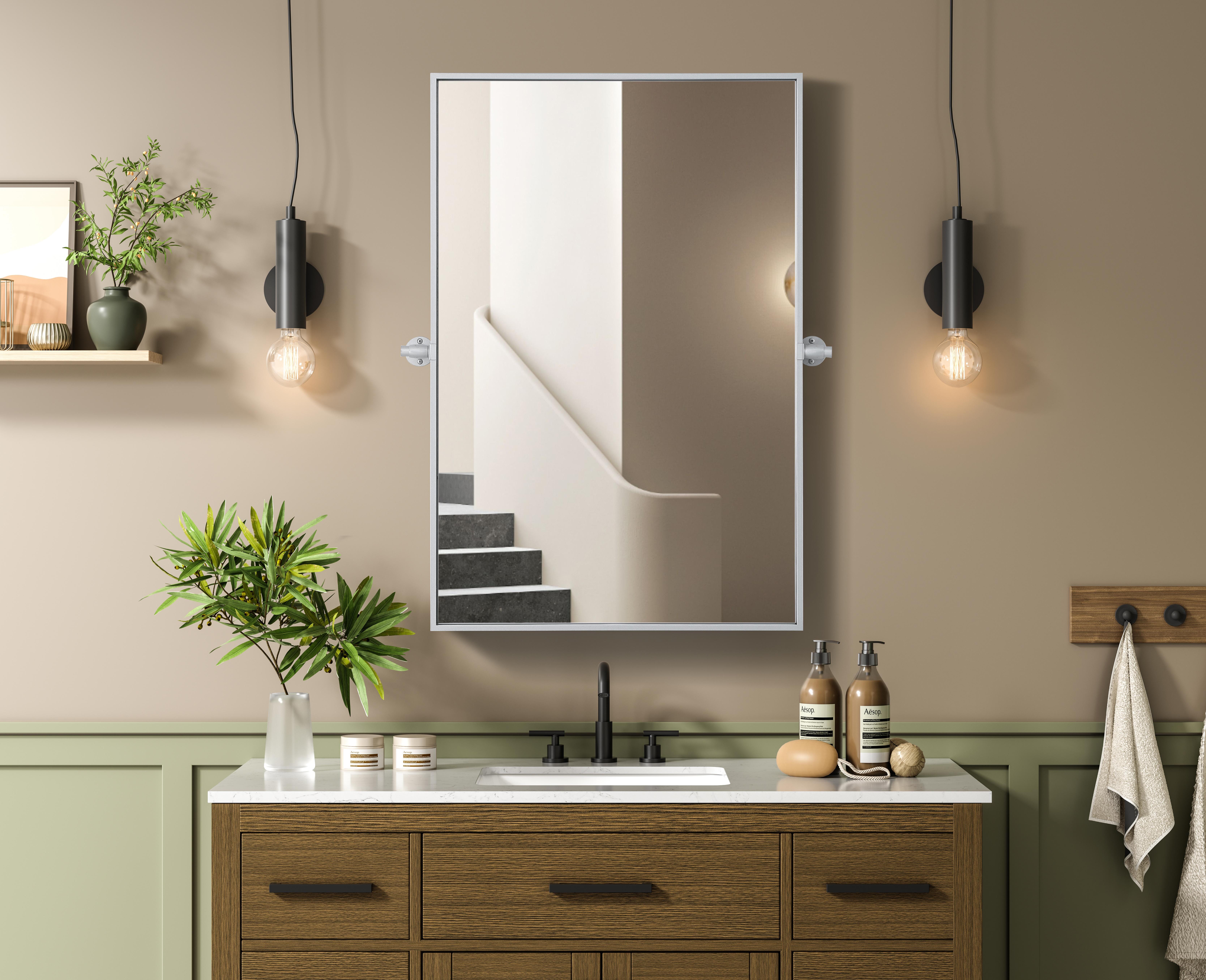 Upgrade your space with a modern pivot mirror that offers both form and function. Featuring an adjustable 8-degree tilt, this mirror allows you to customize your viewing angle for convenience and style. The iron frame with MDF backing ensures durability, while the hand-painted finish—available in black, silver, and brass—adds a touch of sophistication. Designed for versatility, this rectangular mirror can be mounted vertically or horizontally, making it the perfect fit for bathrooms, bedrooms, offices, and more. Its slim metal frame provides a sleek, contemporary aesthetic that blends seamlessly into various design styles. With included mounting brackets and screws, installation is simple and secure, giving your space an instant refresh. Whether you're getting ready for the day or enhancing your home décor, this pivot mirror delivers both style and practicality. Collection: Amoura Rooms: Bathroom Finish: Silver Width: 24.00" Height: 36.00" Weight: 20.00 lb Extension from Wall: 3.00" Material: Iron and MDF Country of Origin: China Safety Rating: Damp Manufacturer Warranty: 1 year limited - alternate view
